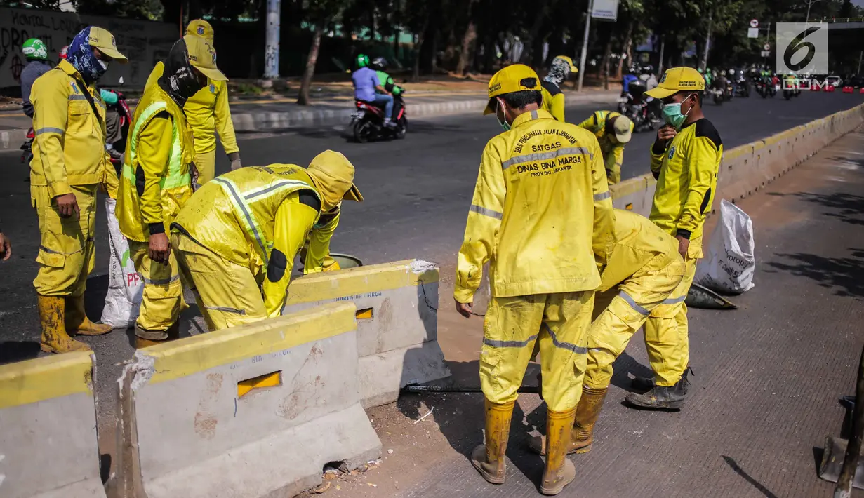 Petugas Dinas Bina Marga DKI Jakarta memperbaiki separator busway di kawasan Jalan Gatot Subroto, Jakarta, Selasa (1/10/2019). Separator busway dirusak massa saat terjadi bentrok antara polisi dengan demonstran di kawasan tersebut. (Liputan6.com/Faizal Fanani)
