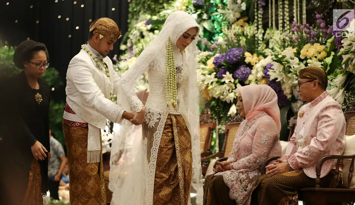 Putra Ketua MPR, Ray Zulham Farras Nugraha merapihkan busana sang istri DR. Milka Anisya Norosiya saat acara pernikahan di Jakarta, Minggu (24/9). Acara pernikahan tersebut di hadiri beberapa Tokoh dan Pejabat Publik. (Liputan6.com/Johan Tallo)