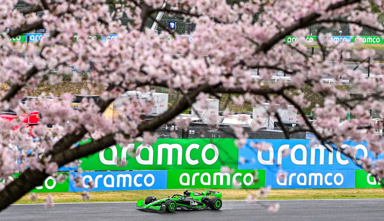 Pembalap Kick Sauber, Zhou Guanyu terlihat memacu mobilnya di antara ranting pohon sakura saat melakukan latihan bebas pertama (FP1) F1 GP Jepang 2024 di Sirkuit Suzuka, Jepang, Jumat (05/04/2024). (AFP/Yuichi Yamazaki)