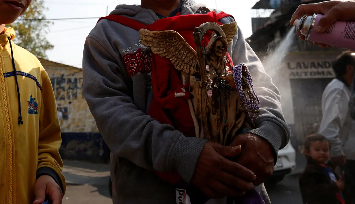 Warga Meksiko membawa patung Santa Muerte berkeliling saat merayakan tahun baru di Meksiko, Minggu (1/1/2017). Santa Muerte dikenal sebagai mahluk pencabut nyawa berwajah tengkorak dengan membawa tongkat bercelurit tajam. (REUTERS/Carlos Jasso)