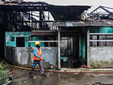 Petugas pemadam kebakaran melintas di depan salah satu rumah warga yang terbakar di Jalan Masjid Alhuda atau depan Stasiun Kebayoran Lama RT 05/01, Jakarta Selatan, Selasa (24/5/2022). Petugas pun mengerahkan 27 unit mobil pemadam kebakaran dari Sudin Damkar Jakarta Selatan ke lokasi kejadian. (Liputan6.com/Johan Tallo)