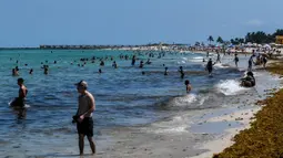 Orang-orang bermain air di Miami Beach, Florida, Rabu (10/6/2020). Pantai Miami dibuka hari ini untuk pertama kalinya setelah hampir tiga bulan ditutup guna menekan jumlah penyebaran corona Covid-19. (CHANDAN KHANNA / AFP)