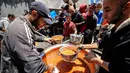 Situasi ini membatasi akses ke lahan pertanian, pasokan makanan, dan layanan penting. Tampak dalam foto, orang-orang berebut untuk mendapatkan makanan hangat di kamp pengungsi Palestina, Nuseirat, Jalur Gaza Tengah pada Kamis 7 Mei 2026. (Eyad Baba/AFP)