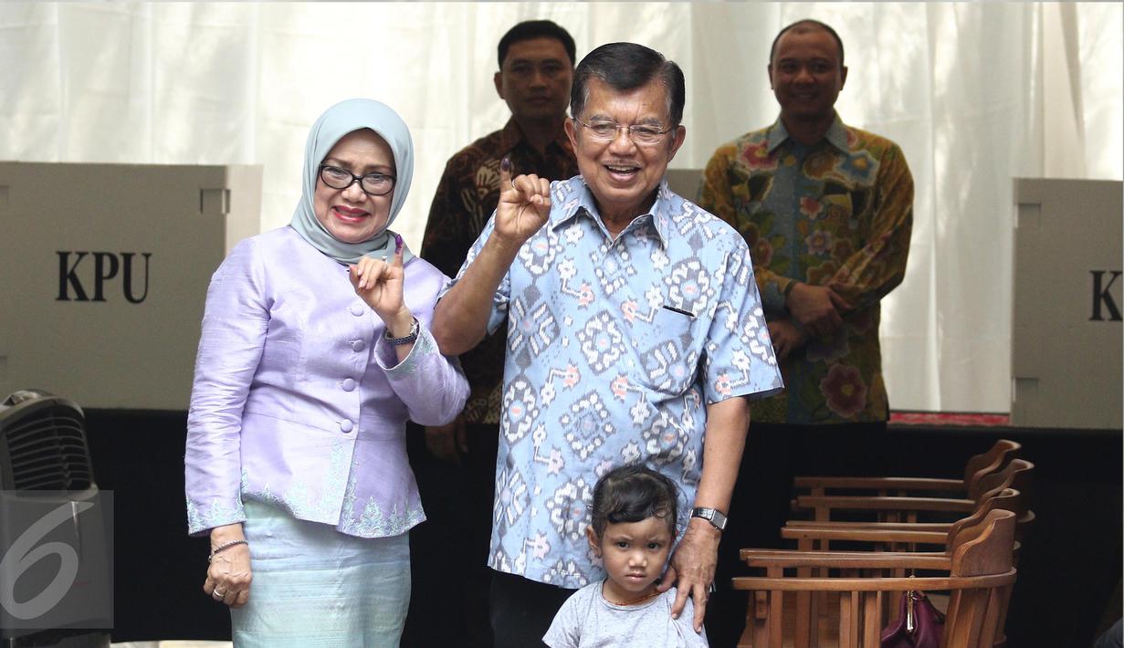 Wakil Presiden Jusuf Kalla (JK) didampingi istri, Mufidah Kalla, menunjukkan jari yang sudah dicelupkan ke tinta setelah melakukan pencoblosan Pilkada DKI 2017 di TPS 03 Kelurahan Pulo, Jakarta Selatan, Rabu (19/4). (Liputan6.com/Herman Zakharia)