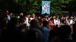 Seorang fans membawa poster Cristiano Ronaldo saat menyambut kedatangan Timnas Portugal di hotel tempat mereka menginap jelang Euro 2024 di Harsewinkel, Jerman, Rabu (13/06/2024) waktu setempat. (AFP/Patricia De Melo Moreira)