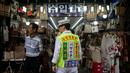 Seorang pria mengenakan rompi saat mengiklankan pakaian, sepatu, dan tas di luar sebuah toko di pasar Namdaemun di Seoul (2/7/2019). Dibangun pada tahun 1946, Pasar Namdaemun merupakan salah satu pasar tradisional yang terbesar di Korea. (AFP Photo/Minji Suh)