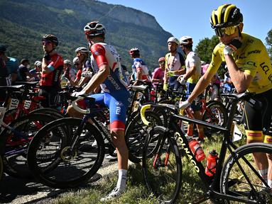 Pembalap UEA Team Emirates sekaligus penyandang Yellow Jersey, Tadej Pogacar sedang menunggu saat regulator balapan menghentikan sementara perlombaan karena demonstrasi perubahan iklim yang menutup rute balapan pada etape ke-10 Tour de France, antara Morzine dan Megeve, di Pegunungan Alpen Prancis, pada 12 Juli 2022. (AFP/Marco Bertorello)