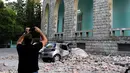 Seorang pria mengabadikan gedung yang runtuh sai gempa berkekuatan 5,6 magnitudo mengguncang Tirana, Albania (21/9/2019). Efek dari gempa bumi tersebut mengakibatkan puluhan bangunan hancur serta memicu pemadaman listrik di ibu kota Tirana. (AFP Photo/Gent Shkullaku)