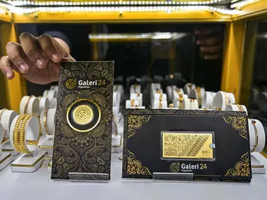 Salah satu karyawan memperlihatkan lembaran emas yang dipajang di Galeri 24, Surabaya, Jawa Timur, pada Kamis 16 Oktober 2025. (Juni KRISWANTO/AFP)