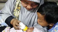 Warga menggendong bayi sambil memberi susu botol saat di Polsek Batuaji dan bayi ini ditemukan didalam koper di Perumahan Villa Paradise, Batuaji, Selasa (9/1). (Dalil Harahap/Batam Pos/Jawa Pos Group)