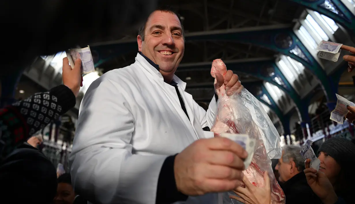 Seorang penjual melelang potongan daging kepada pembeli selama lelang tahunan menyambut malam Natal di Smithfield Market, London, Selasa (24/12/2019). Operasi pasar ini menjadi sarana menghabiskan persediaan para pemilik toko jelang tahun baru. (DANIEL LEAL-OLIVAS / AFP)