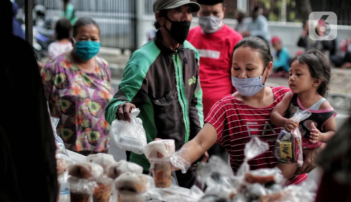Warga mengambil takjil yang dibagikan di Jalan Cempaka Putih Raya, Jakarta, Senin (11/5/2020). Setiap hari selama Ramadan, masyarakat sekitar membagikan 350 takjil kepada warga kurang mampu dan terdampak virus corona COVID-19. (Liputan6.com/Johan Tallo)