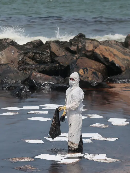Penjaga pantai Sri Lanka mengenakan pakaian khusus saat membersihkan tumpahan minyak di sebuah pantai di Uswetakeiyawa, Kolombo, Senin (10/9). Tumpahan minyak disebabkan oleh kebocoran pipa. (AP Photo/Eranga Jayawardena)