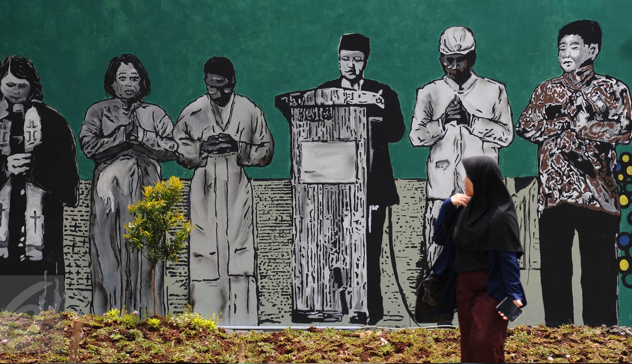 Warga melintas di depan gambar pemimpin agama di Lapangan Kebagusan, Jakarta, Rabu (15/2). Jelang menggunakan hak pilihnya pada Pilkada, Ketua Umum PDI-P Megawati Soekarnoputri menggoreskan tinta pada salah satu gambar. (Liputan6.com/Helmi Fithriansyah)