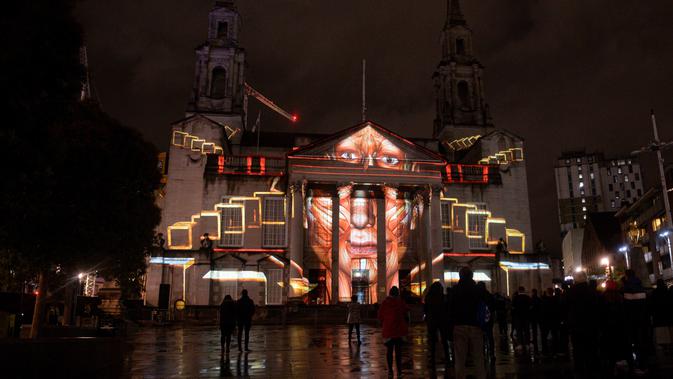 Masyarakat mengagumi instalasi seni bercahaya bertajuk 'Telekinetic Rumours' karya seniman Polandia Pani Pawlosky yang diproyeksikan di Balai Kota Leeds, utara Inggris, 10 Oktober 2019. Festival mengambil alih jalanan pusat kota Leeds selama dua malam di bulan Oktober. (Oli SCARFF/AFP)