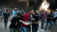 Para pengunjuk rasa Palestina mengevakuasi seorang pria yang terluka dalam bentrokan Jumat (12/10) di sepanjang pagar yang memisahkan Israel dan Gaza yang dikuasai Hamas. (Khalil Hamra/AP)