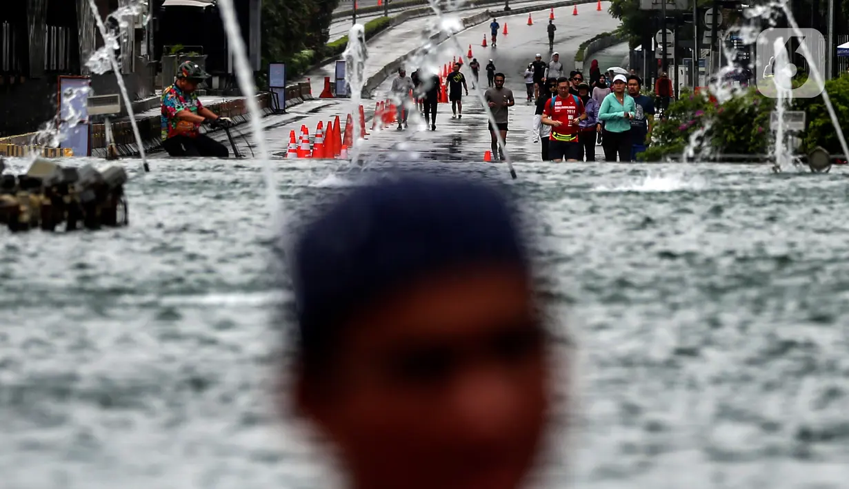 Warga berolahraga di tengah rintik hujan pada Car Free Day atau hari bebas kendaraan di kawasan Bundaran Hotel Indonesia (HI), Jakarta, Minggu (12/2/2023). Hujan telah melanda wilayah Jakarta sejak Sabtu. Terlihat, hingga Minggu pagi, hujan masih terus melanda area ibu kota.(Liputan6.com/Johan Tallo)