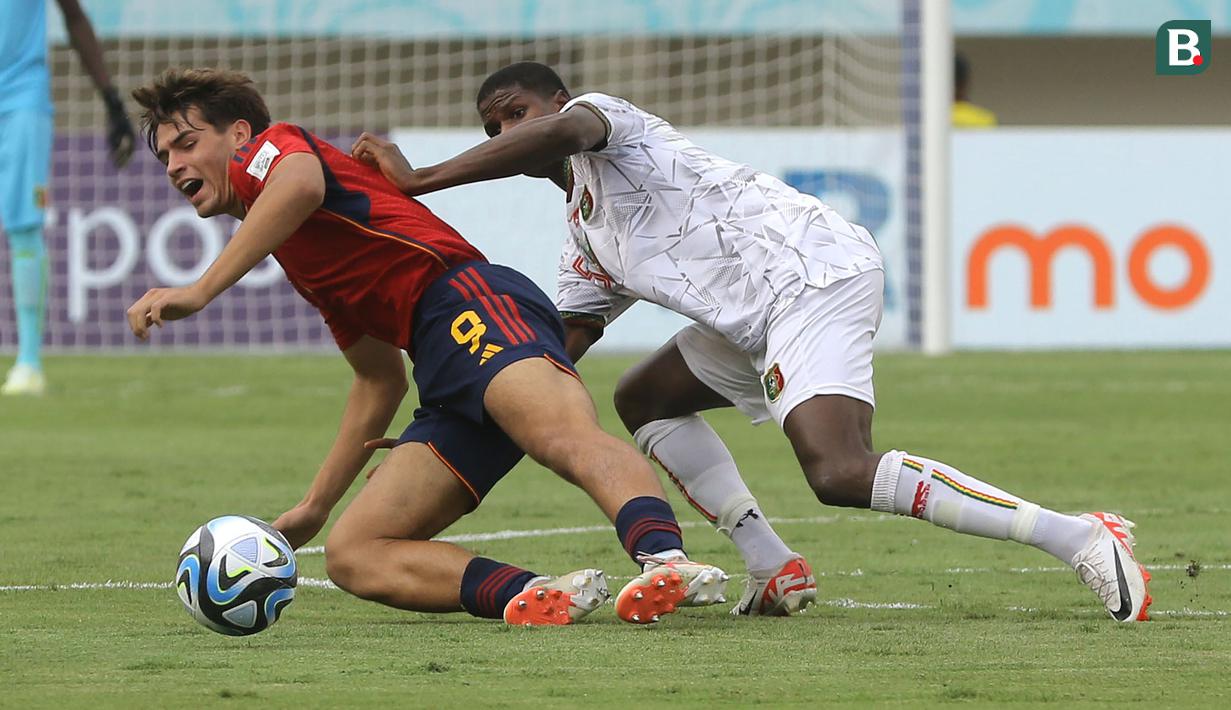 <p>Pemain Timnas Spanyol U-17, Marc Guiu (kiri) berduel dengan pemain Mali U-17, Issa Traore dalam pertandingan babak penyisihan Grup B Piala Dunia U-17 di Stadion Manahan, Solo, Senin (13/11/2023). (Bola.com/Arief Bagus)</p>