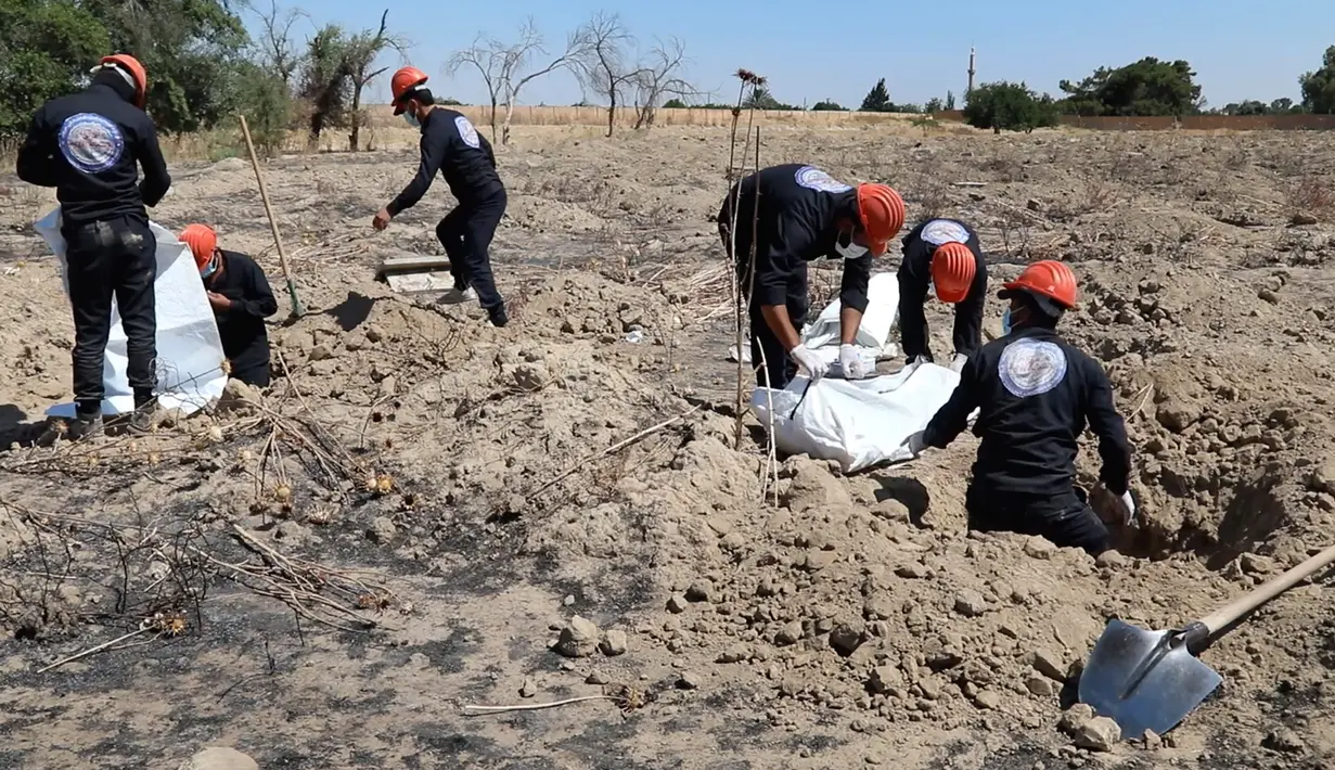 Gambar dari video pada 14 Juli 2019, pekerja Dewan Sipil Raqqa menggali kuburan massal berisi tulang belulang manusia di Raqqa, Suriah, 14 Juli 2019. Sejauh ini para pekerja telah menemukan 313 mayat dari kuburan massal yang ditemukan bulan lalu di dekat kota di Suriah utara tersebut. (AP Photo)
