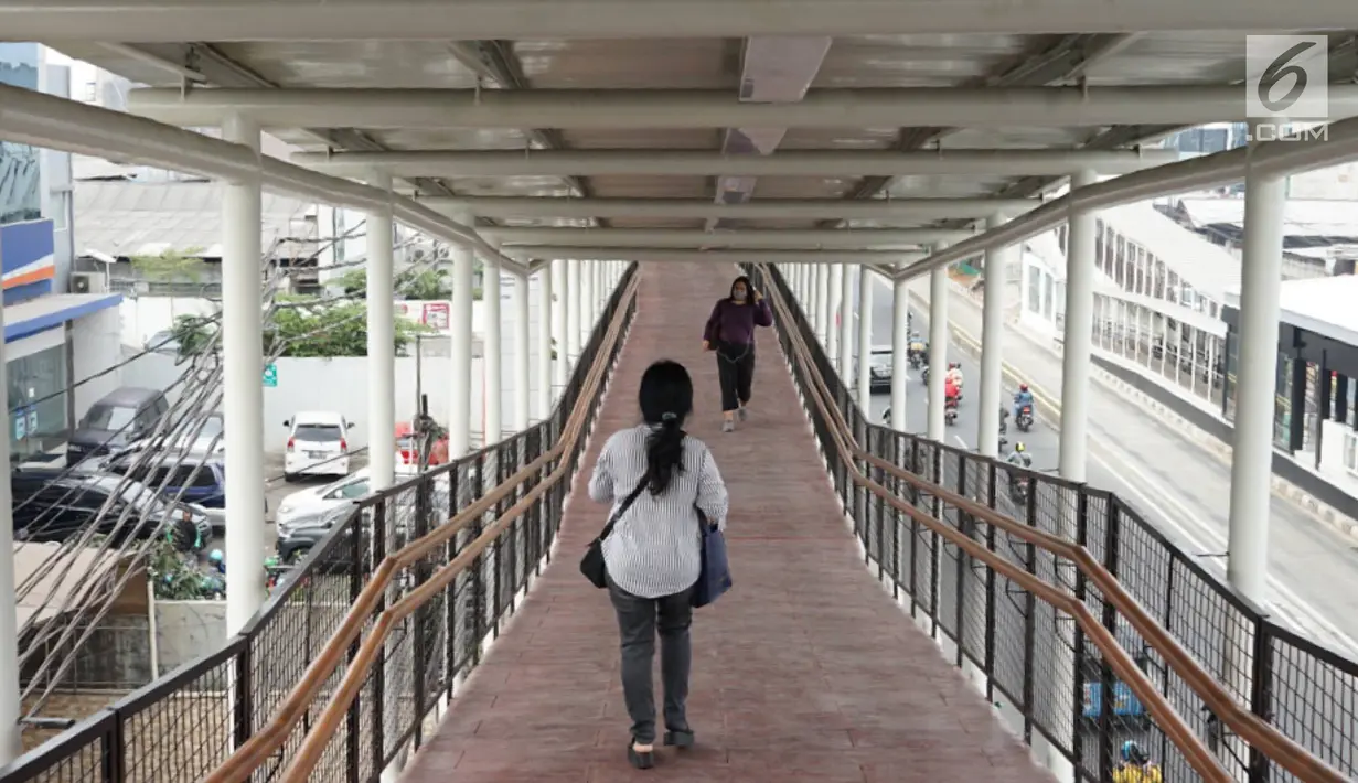 Warga melintasi jembatan penyeberangan (Skybridge) yang menghubungkan Stasiun LRT Velodrome dengan Halte Transjakarta Pemuda di Rawamangun, Jakarta, Senin (29/7/2019). Skybridge berdesain artistik tersebut memiliki panjang sekitar 500 meter dan lebar 2 meter. (Liputan6.com/Immanuel Antonius)