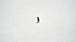 Seorang pria berjalan di Salar de Uyuni, dataran garam terluas di dunia yang terletak di Altiplano, barat daya Bolivia, 28 September 2019. Permukaan Salar de Uyuni tertutup lapisan garam setinggi beberapa kaki, menjadikan dataran ini tetap kering sepanjang tahun. (Photo by Aizar RALDES / AFP)