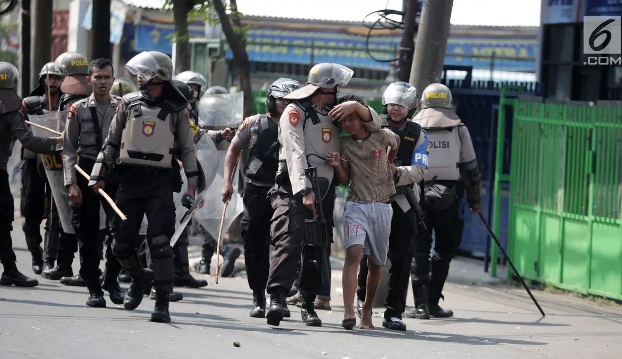 Polisi menangkap seorang pria saat tarjadi bentrok dengan massa di kawasan Petamburan, Jakarta Barat, Rabu (22/5/2019). Kapolres Metro Jakarta Barat Kombes Hengki Haryadi mengatakan ada 99 orang diamankan di Polres Jakarta Barat dan Polda Metro Jaya. (Liputan6.com/Faizal Fanani)