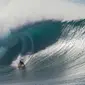 Peselancar John Florence menjelajah ombak besar di Pantai Utara O’ahu, Hawaii, Senin (26/11). (Brian Bielmann / AFP)