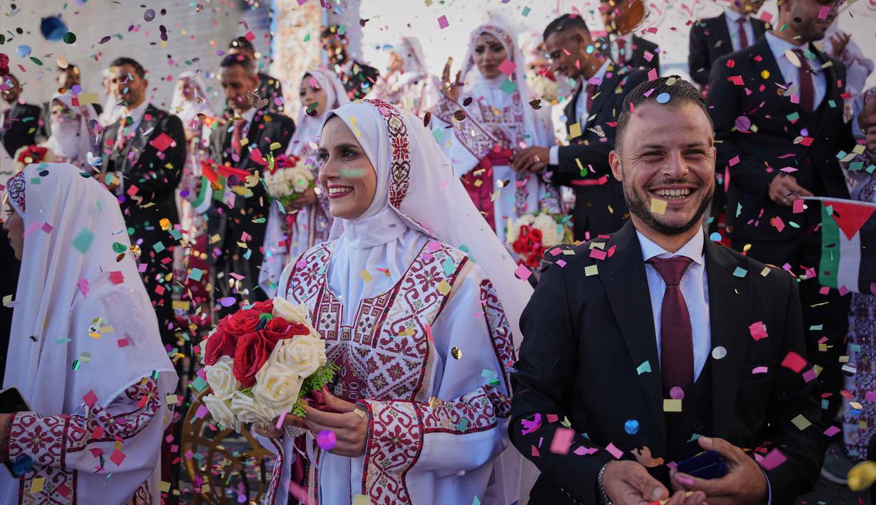 Pasangan Palestina berpartisipasi dalam upacara pernikahan massal di Kota Hamad, Khan Younis, Jalur Gaza, Selasa 2 Desember 2025. 54 pasangan muda Palestina di Gaza melangsungkan pernikahan massal pada Selasa (2/12/2025). (AP Photo/Abdel Kareem Hana)