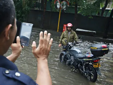Warga berpose disamping motor saat banjir menggenangi kawasan Sunter, Jakarta, Kamis (25/2). Hujan deras yang mengguyur Jakarta serta sistem drainase yang buruk menjadi penyebab banjir sehingga mengganggu aktivitas warga. (Liputan6.com/Immanuel Antonius)