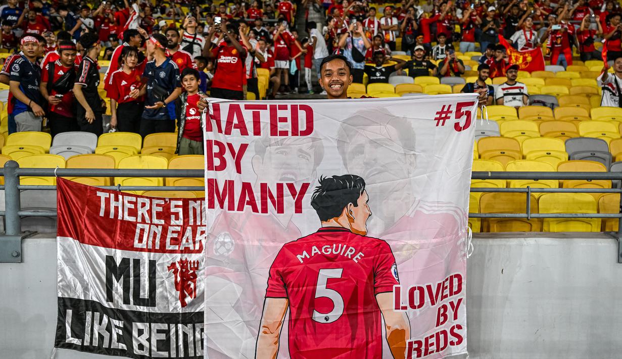 Seorang pendukung Manchester United membentangkan banner bergambar kapten tim, Harry Maguire dalam laga persahabatan melawan ASEAN All-Stars yang berlangsung di Stadion Bukit Jalil, Malaysia, pada hari Rabu (28/5/2025) malam waktu setempat. (AFP/Mohd Rasfan)