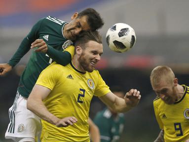 Duel pemain Meksiko, Rafael Marquez (kiri) dengan pemain Skotlandia, Stephen O'Donnell (tengah) pada laga uji coba di Azteca Stadium, Meksiko City, (2/6/2018). Meksiko menang 1-0. (AP/Rebecca Blackwell)
