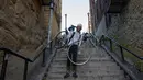 Elliott Raylassi, seorang penduduk lokal sejak tahun 2001, membawa sepedanya menaiki tangga di kawasan Bronx, New York, 23 Oktober 2019. Wisatawan memadati tangga panjang itu untuk berpose ala Joker atau sekadar mengunggahnya di Instagram. (Don Emmert / AFP)