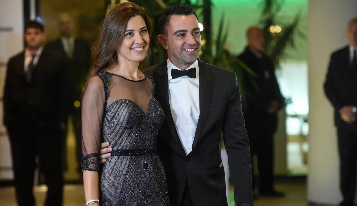 Xavi Hernandez bersama istrinya berpose di karpet merah saat menghadiri pernikahan Lionel Messi di Rosario, Argentina (30/6). Pernikahan Lionel Messi ini dihadiri 260 tamu VVIP. (AFP Photo/Eitan Abramovich)
