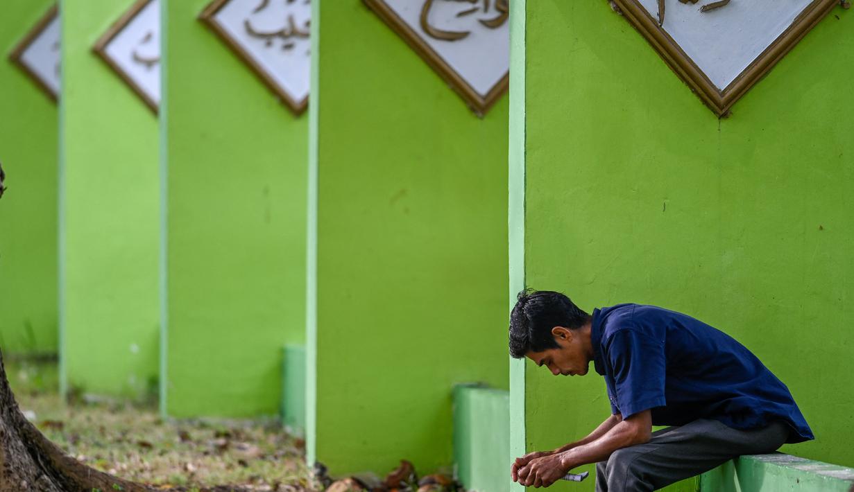 <p>Seorang pria berdoa saat memperingati 18 tahun musibah gempa dan tsunami di kuburan massal Siron, Aceh, Senin (26/12/2022). Sejumlah warga mendatangi Kuburan Massal Siron untuk memenjatkan doa saat peringatan 18 tahun musibah gempa dan tsunami Aceh 2004. (AFP/Chaideer Mahyuddin)</p>