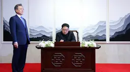 Pemimpin Korea Utara, Kim Jong-un menandatangani buku tamu di Peace House Panmunjom di sebelah Presiden Korea Selatan, Moon Jae-in sebelum melakukan pertemuan antar-Korea, Jumat (2/4). (Korea Summit Press Pool via AP)