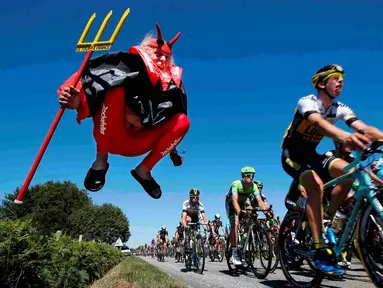 Pebalap sedang melewati Didi Senft, seorang penggemar balap sepeda yang dikenal dengan nama 'El Diablo' (The Devil) di Etape 7 Tour de France yang berjarak 190.5-km dari Livarot ke Fougeres, Prancis, (10/7/2015). (REUTERS/Eric Gaillard)