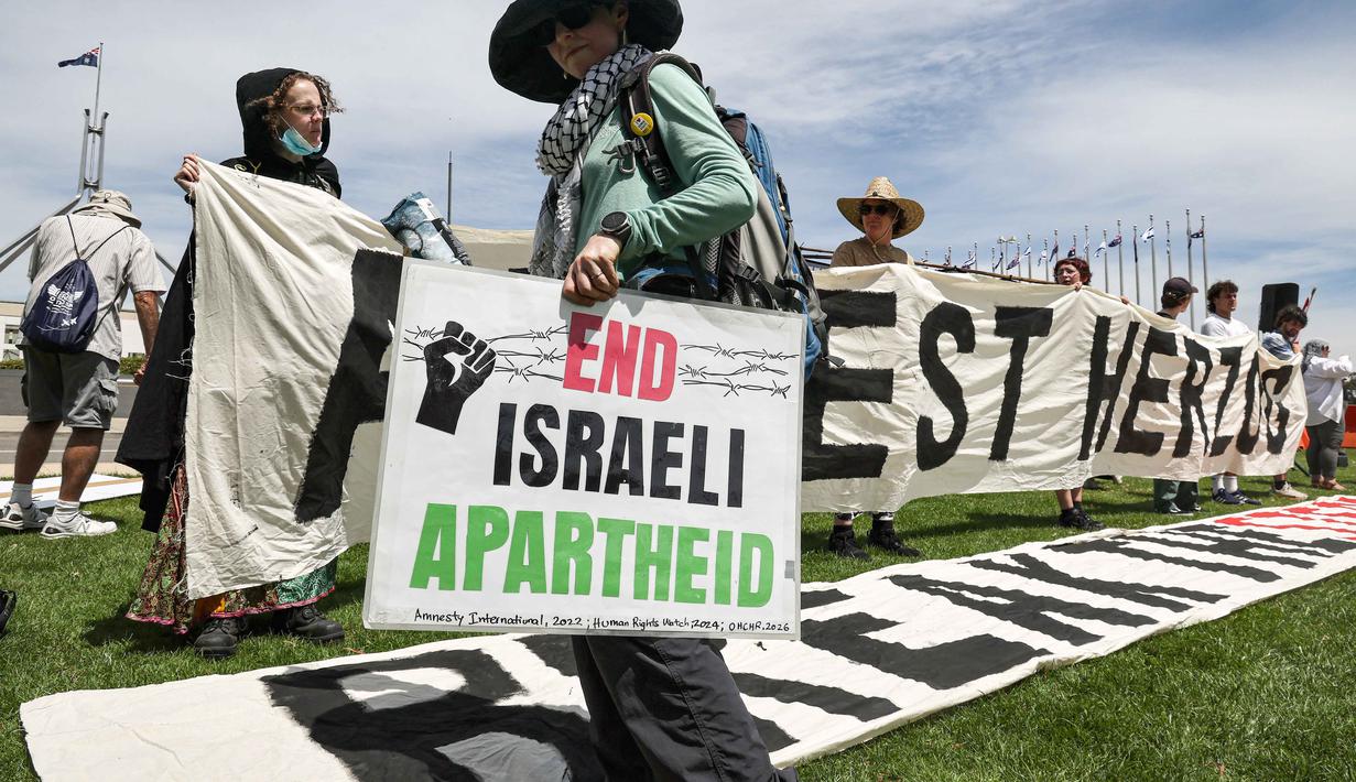 Pengunjuk rasa menolak kehadiran Isaac Herzog karena kebijakan Israel di Gaza. Tampak dalam foto, para pengunjuk rasa berkumpul di depan gedung Parlemen menjelang pertemuan antara Perdana Menteri Australia Anthony Albanese dan Presiden Israel Isaac Herzog di Canberra pada Rabu 11 Februari 2026. (David GRAY/AFP)