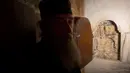 Seorang imam Yunani berdiri di dekat jendela ruang pemakaman makam Yesus di Gereja Makam Kudus di Yerusalem (20/3). Setelah tertunda selama lebih dari 200 tahun, akhirnya restorasi dan renovasi makam Yesus hampir selesai. (AP Photo/Sebastian Scheiner)