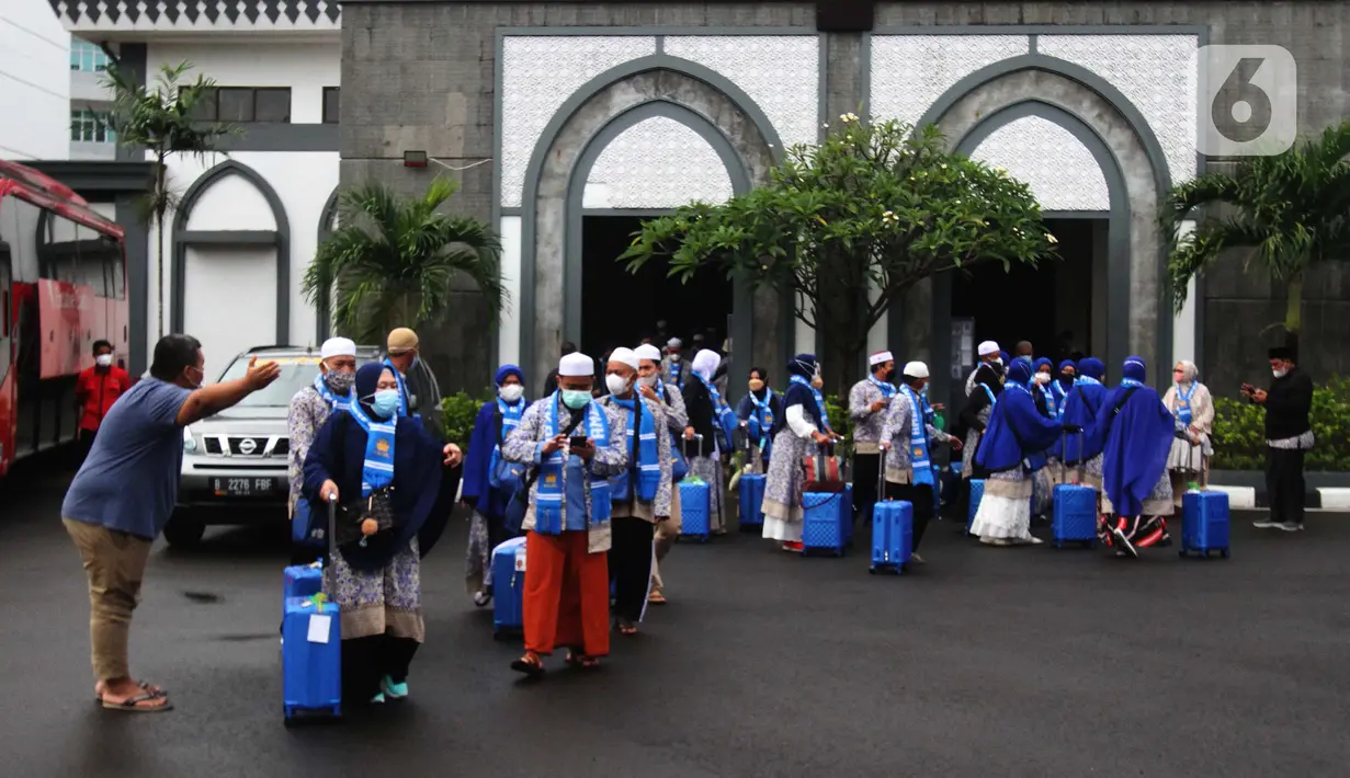 Seorang pria mengarahkan jemaah umrah menuju bus untuk diberangkatkan usai masa karantina di Asrama Haji Pondok Gede, Jakarta, Selasa (11/1/2022). Sebanyak 436 calon jemaah umrah diberangkatkan setelah sebelumnya pemerintah memberangkatkan 419 jemaah seluruh Indonesia.  (merdeka.com/Imam Buhori)