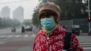 Seorang wanita beraktivitas mengenakan masker pelindung untuk menghindari polusi udara buruk di Beijing (22/10). (AFP Photo/Nicolas Asfaouri)