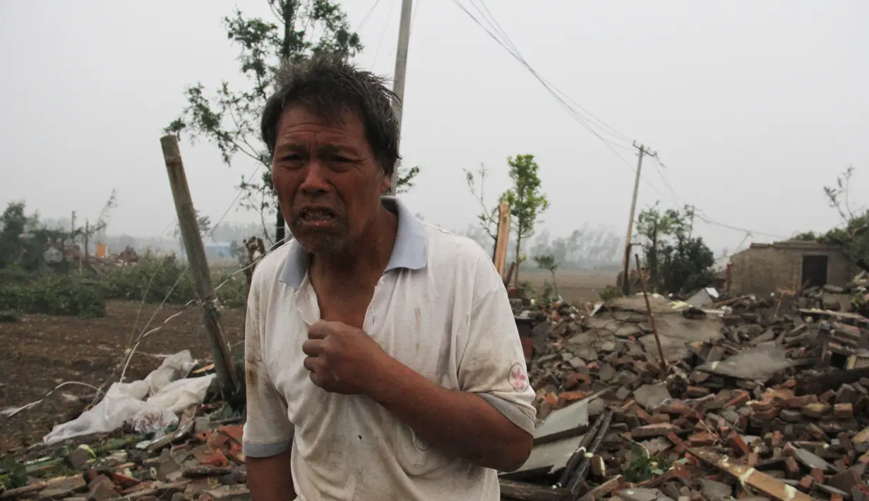 Seorang pria berdiri di depan puing bangunan rumahnya akibat tornado menyapu wilayah Yancheng, Provinsi Jiangsu, Tiongkok, Kamis (23/6). Cuaca ekstrim termasuk hujan es, hujan lebat, dan angin puting beliung itu menewaskan sedikitnya 51 orang. (STR/AFP)