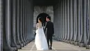 Sepasang calon pengantin asal Asia melakukan foto prewedding di bawah Jembatan Pont de Bir Hakeim, di atas permukaan sungai Seine ketika matahari terbit di Paris, 25 Juli 2017. (AFP PHOTO / LUDOVIC MARIN)