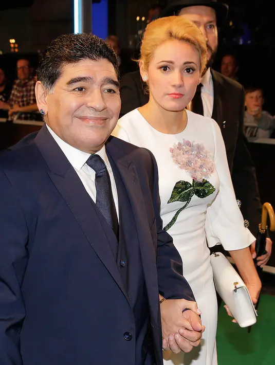 Pesepakbola legendaris Argentina, Diego Maradona mengandeng tangan kekasihnya, Rocio Oliva saat tiba menghadiri The Best FIFA Football Awards 2017 di London, (23/10). Rocio Oliva merupakan mantan pemain sepak bola wanita. (AP Photo/Alastair Grant)