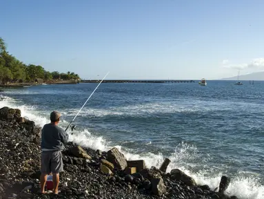 Seorang pria memancing dipinggir pantai di Lahaina, Maui, Hawaii, Rabu (30/7/2015) . Maui adalah pulau terbesar kedua di Hawai yang memiliki pemandangan menakjubkan. (REUTERS/Marco Garcia)