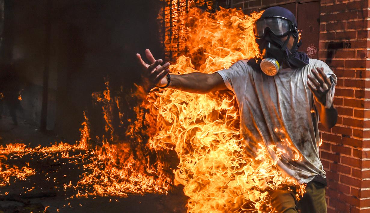 Seorang demonstran terbakar saat unjuk rasa menentang Presiden Venezuela, Nicolas Maduro di Caracas, Rabu (3/5). Pria tersebut tersulut api dari ledakan tangki sepeda motor milik polisi saat unjuk rasa yang diwarnai bentrokan. (RONALDO SCHEMIDT / AFP)