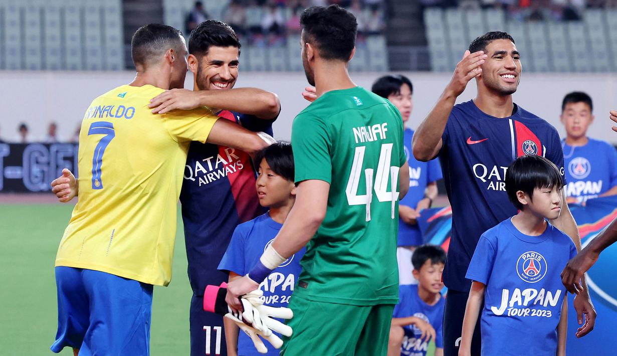 Pemain Al Nassr, Cristiano Ronaldo (kiri), menyapa pemain PSG, Marco Asensio sebelum pertandingan uji coba yang berlangsung di Nagai Stadium, Osaka, Selasa (25/7/2023). Kedua pemain tersebut pernah bermain bersama untuk Real Madrid. (AFP/Paul Miller)
