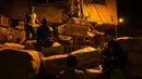 Sejumlah buruh duduk di dekat tumpukan barang di kawasan tua New Delhi, India (6/3). Karena tuntutan ekonomi para buruh India ini harus rela hidup seadanya, bahkan mereka masih bekerja hingga larut malam. (AFP Photo/Chandan Khanna)