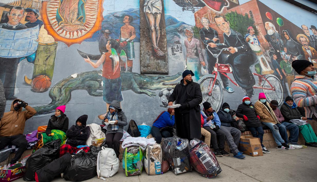 Para imigran makan dan menunggu bantuan saat berkemah di sebuah jalan di pusat kota El Paso, Texas, Amerika Serikat, 18 Desember 2022. Kota-kota perbatasan Texas bersiap menghadapi lonjakan sebanyak 5.000 imigran baru setiap hari yang melintasi perbatasan AS-Meksiko karena pembatasan imigrasi era pandemi berakhir minggu ini. (AP Photo/Andres Leighton)