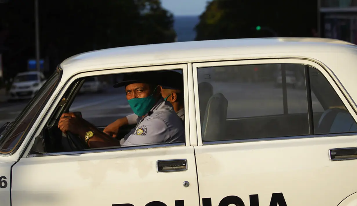 Polisi yang mengenakan masker berpatroli di jalanan kosong saat penerapan jam malam di Havana, Kuba, Selasa (1/9/2020). Otoritas Kuba menerapkan lockdown selama 15 hari di Havana untuk keluar dari penularan COVID-19 tingkat rendah tetapi terus-menerus. (AP Photo/Ramon Espinosa)