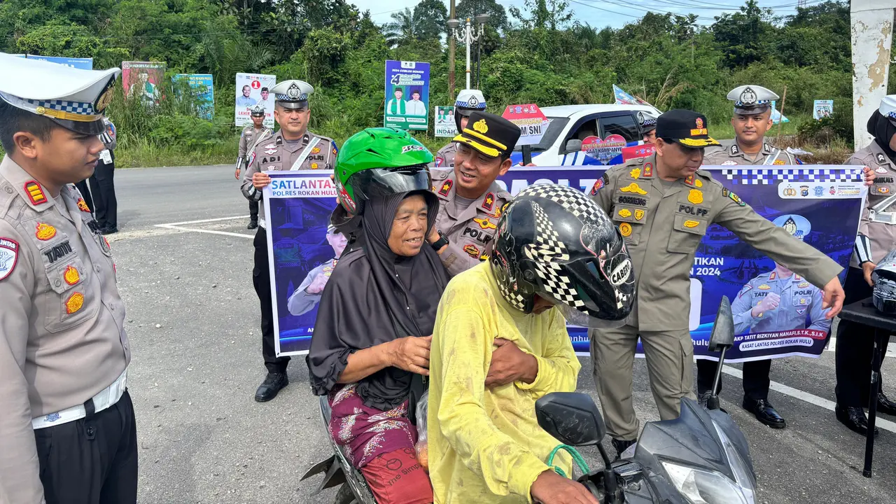 Polres Rokan Hulu membagikan helm kepada warga yang kedapatan tidak memakai helm saat naik motor.